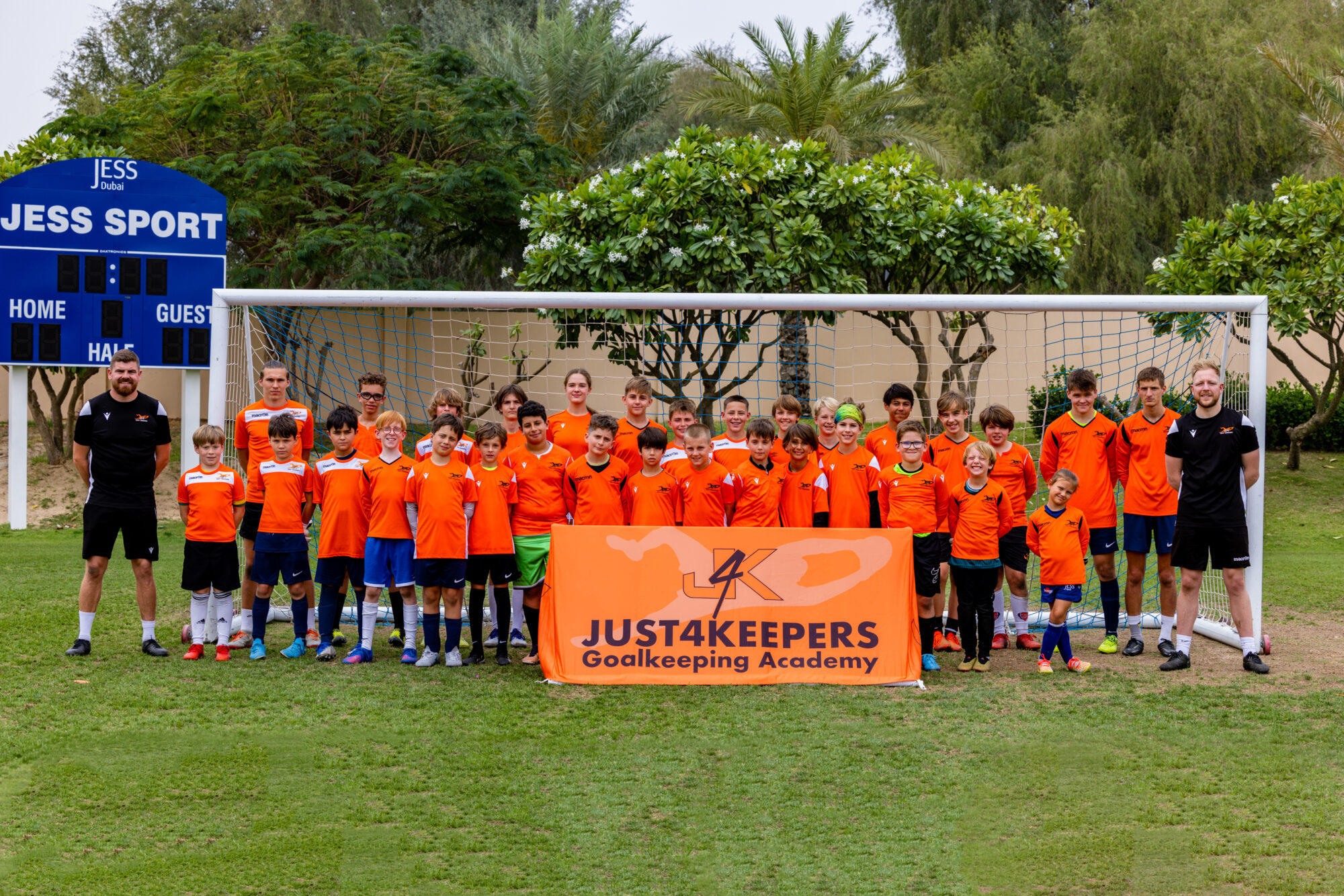 Group of children and coaches in behind a banner