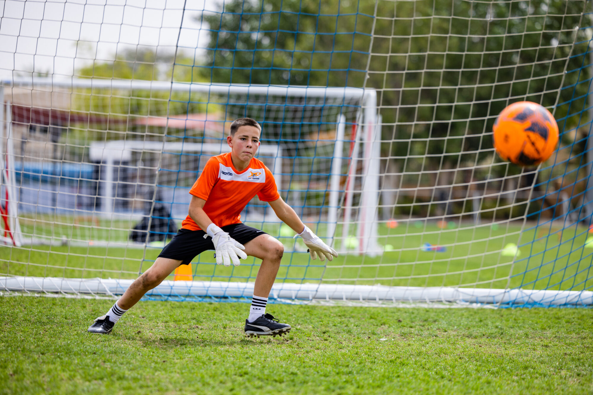 Child in orange t shirt stepping towards a flying football