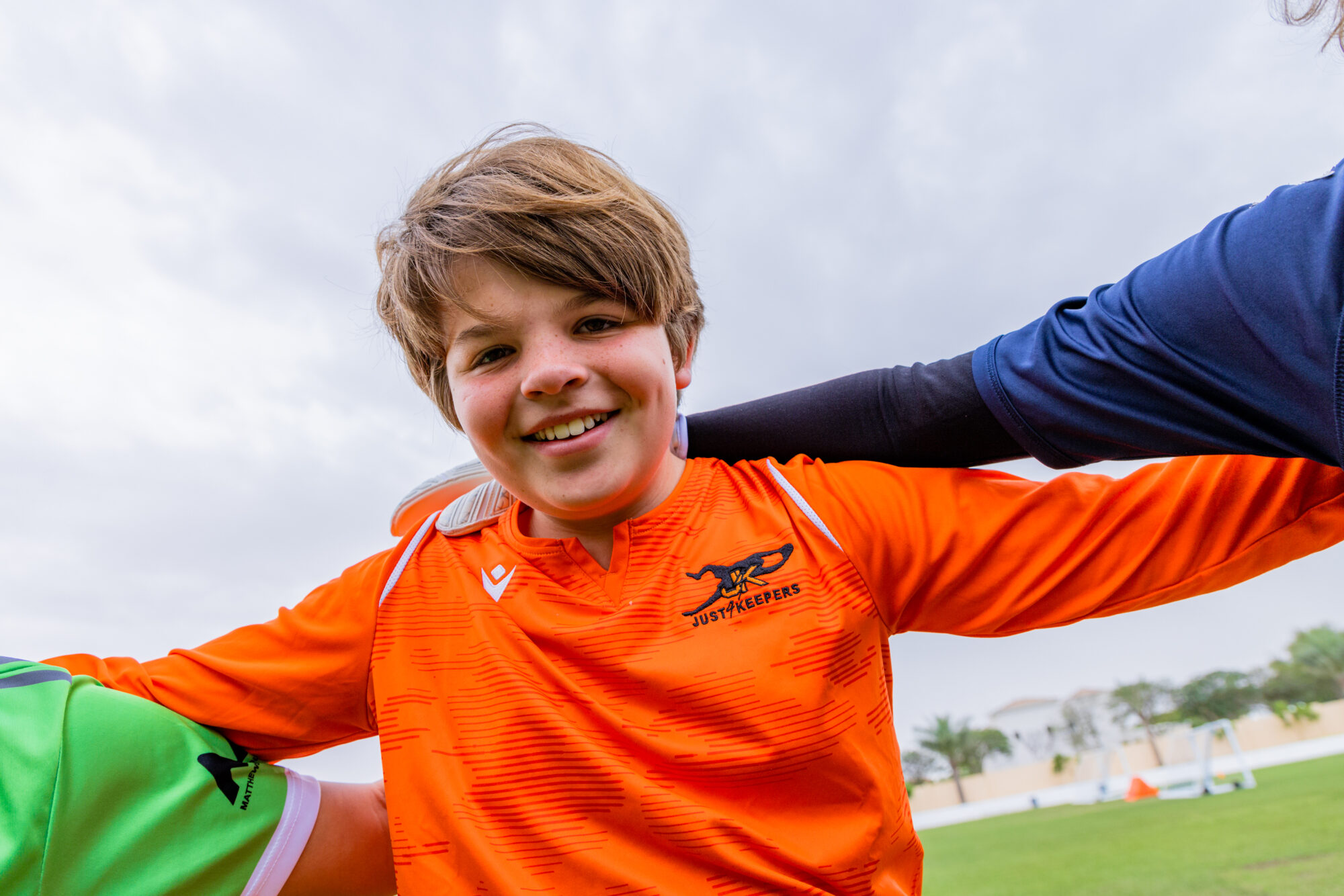 Goalkeeper smiling with arms around someone else